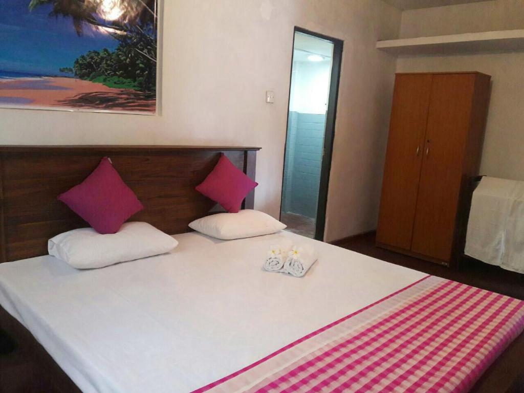 a bedroom with a large bed with pink and white pillows at Dinky in Hikkaduwa