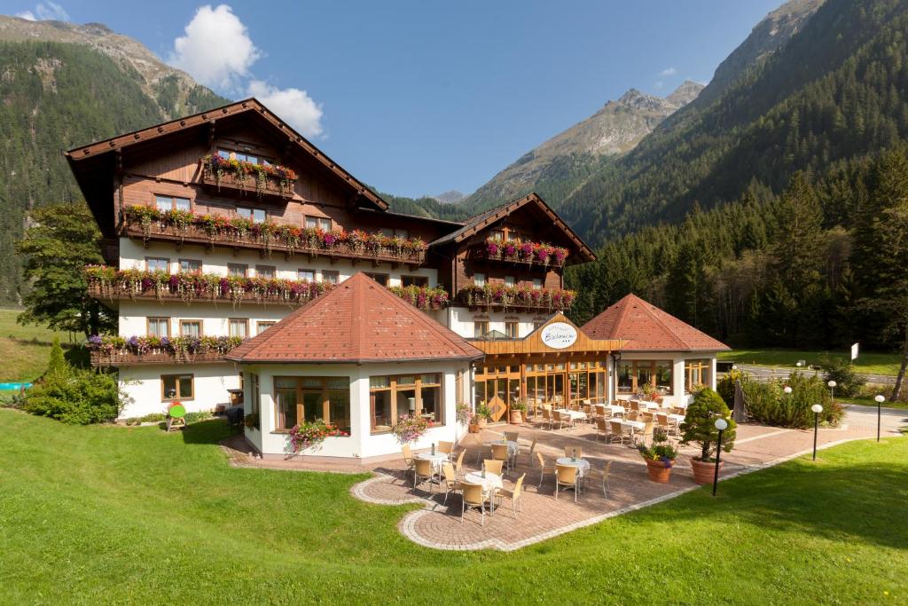 ein Gebäude mit Tischen und Stühlen davor in der Unterkunft Alpenhotel Badmeister in Flattach