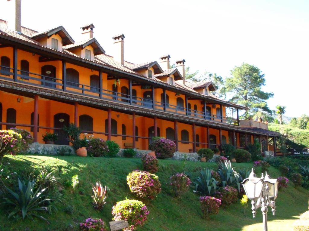 an orange building with a garden in front of it at Hotel Pousada Boa Montanha in Monte Verde