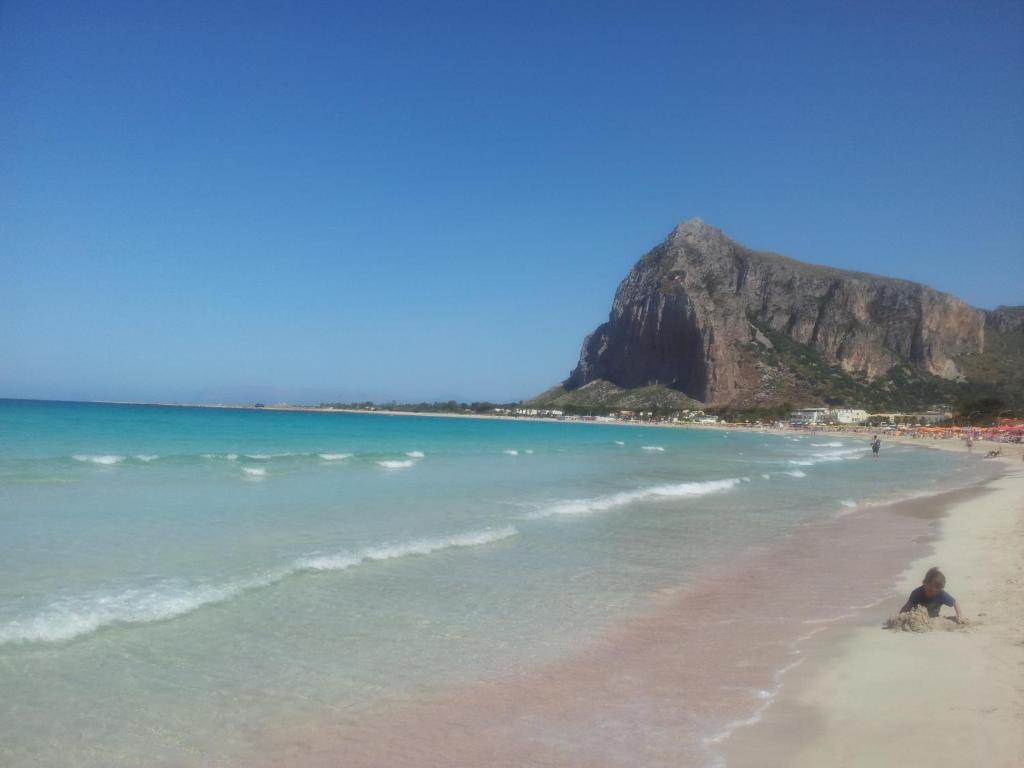 a person sitting on a beach with the ocean at HOME HOLIDAY PINO&FABIANA in San Vito lo Capo