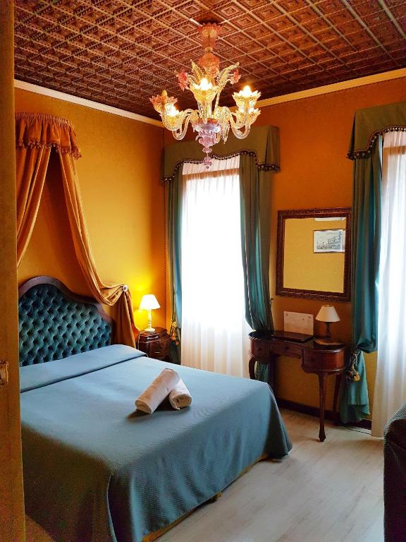 a bedroom with a blue bed and a chandelier at San Gallo Hotel in Venice