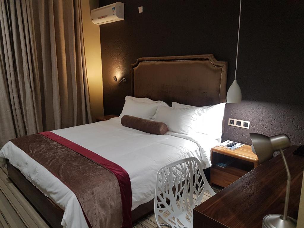a hotel room with a bed and a desk with a lamp at La Signature Guest house in Francistown