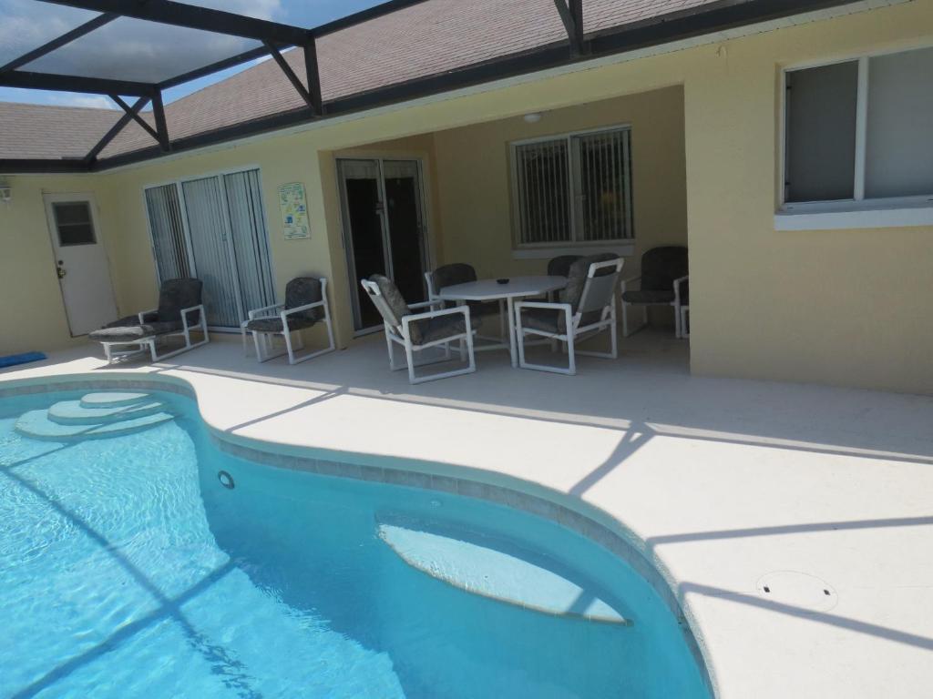 a swimming pool in front of a house with a table and chairs at 3 Bedroom Standard Davenport Home FL 33897 in Orlando