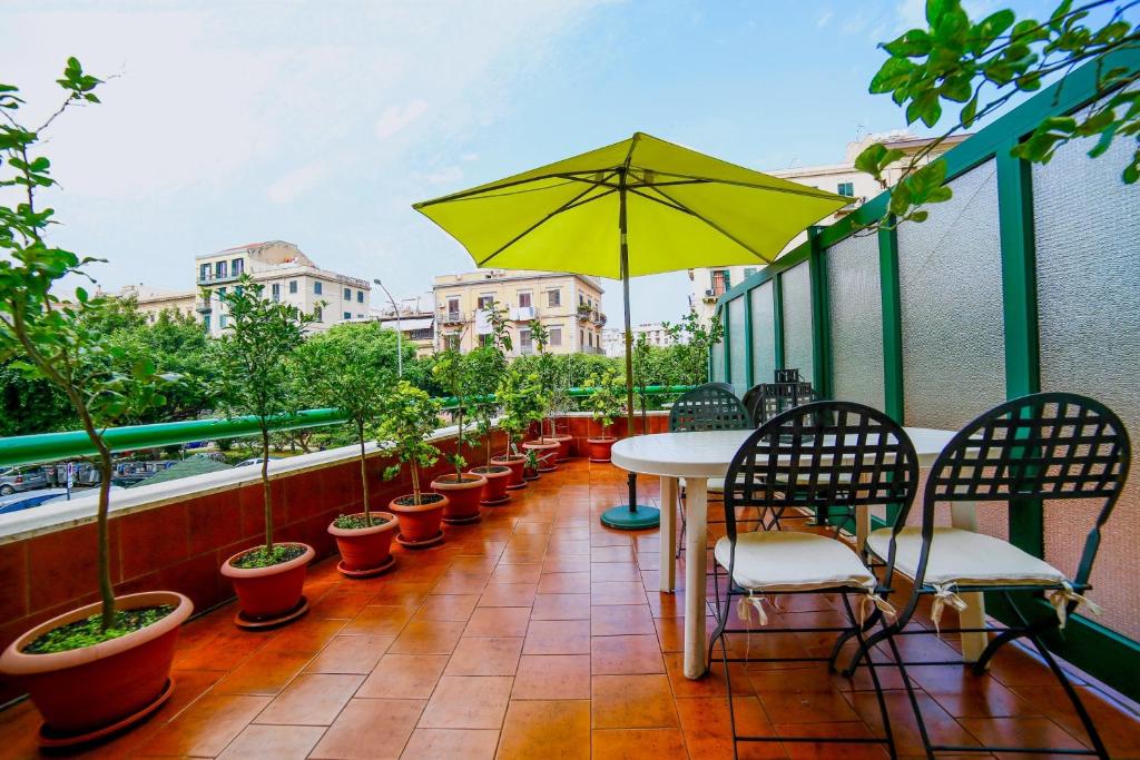 een balkon met een tafel en stoelen en een gele parasol bij Amazing Politeama House in Palermo