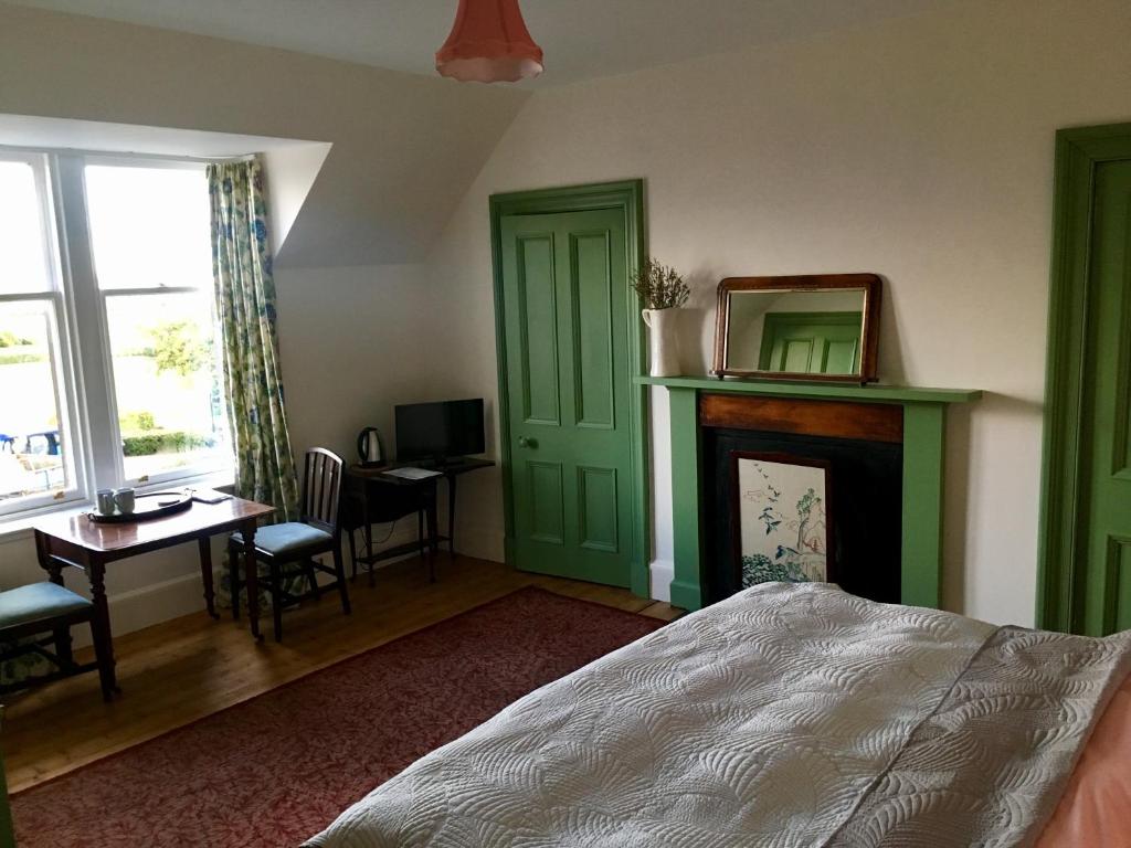 a bedroom with a bed and a desk and a fireplace at Denson Villa in Nairn