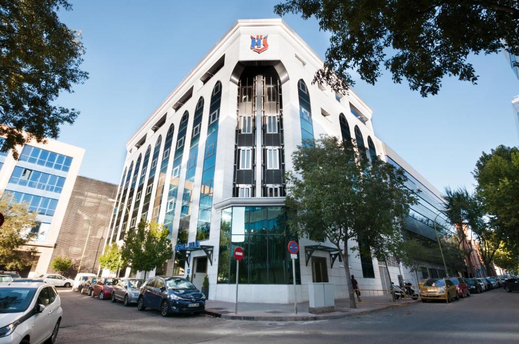 un edificio blanco con coches estacionados frente a él en Hotel Julia, en Madrid