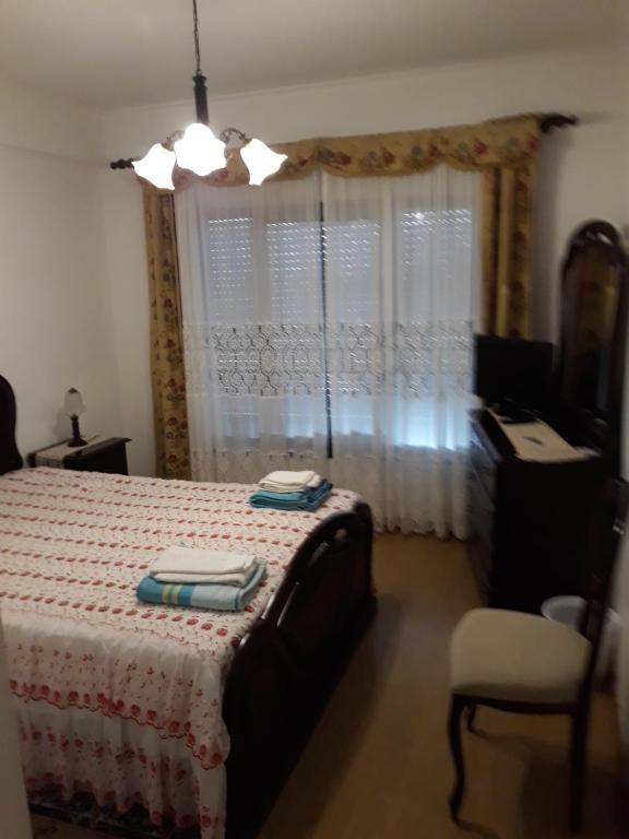 um quarto com uma cama, uma cadeira e uma janela em Apartamento do Paim em Ponta Delgada