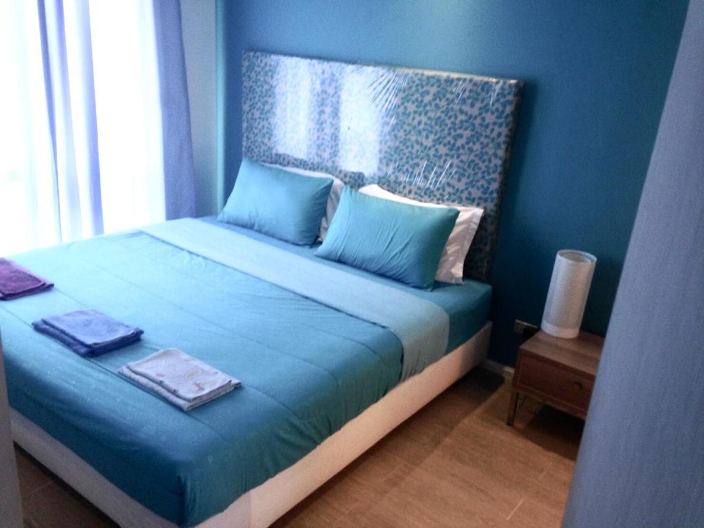 um quarto azul com uma cama com lençóis azuis e uma janela em Atlantis Condo Resort Jomtian Pattaya em Praia de Jomtien