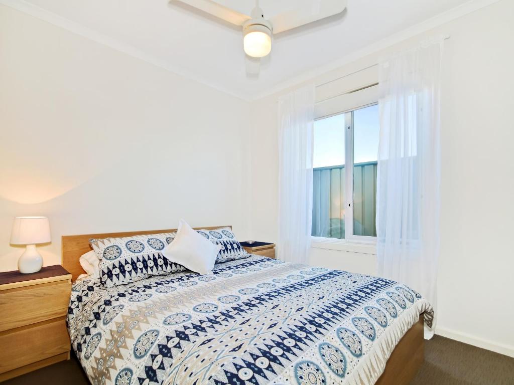 a white bedroom with a bed and a window at Sunset at Snapper Point - Aldinga Beach - C21 SouthCoast Holidays in Aldinga Beach