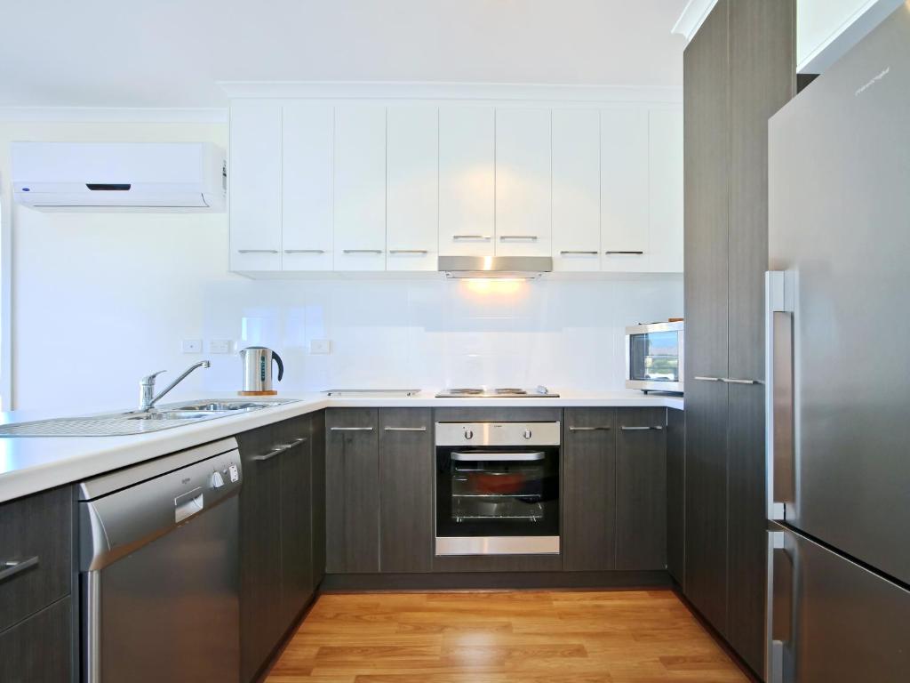 a kitchen with white cabinets and stainless steel appliances at Sunset at Snapper Point - Aldinga Beach - C21 SouthCoast Holidays in Aldinga Beach