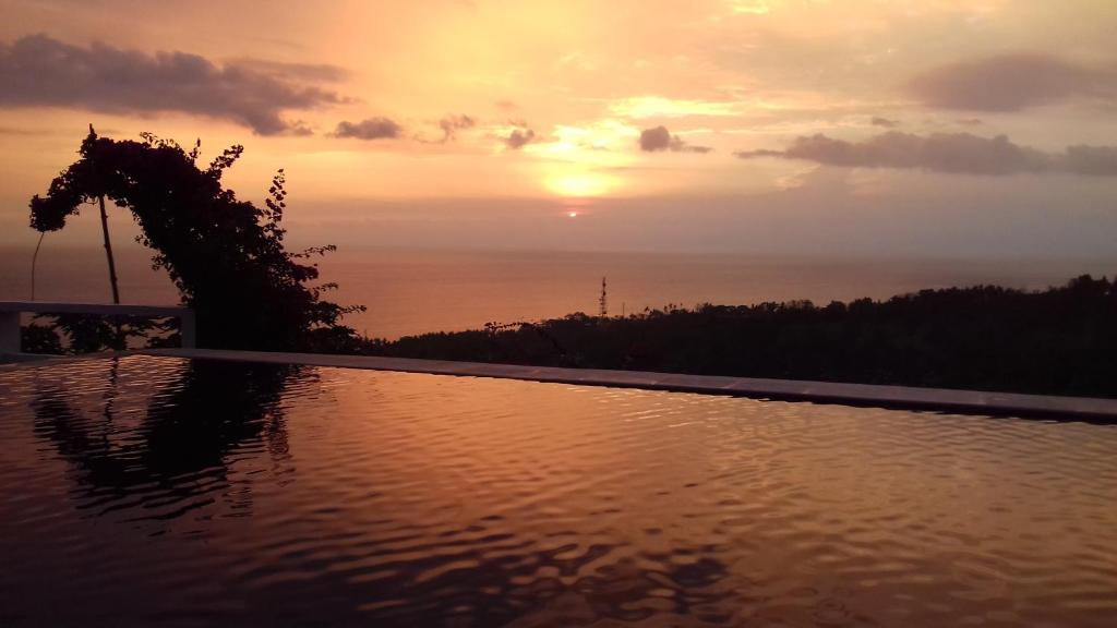 a swimming pool with the sunset in the background at Rara Villas Lombok in Senggigi 