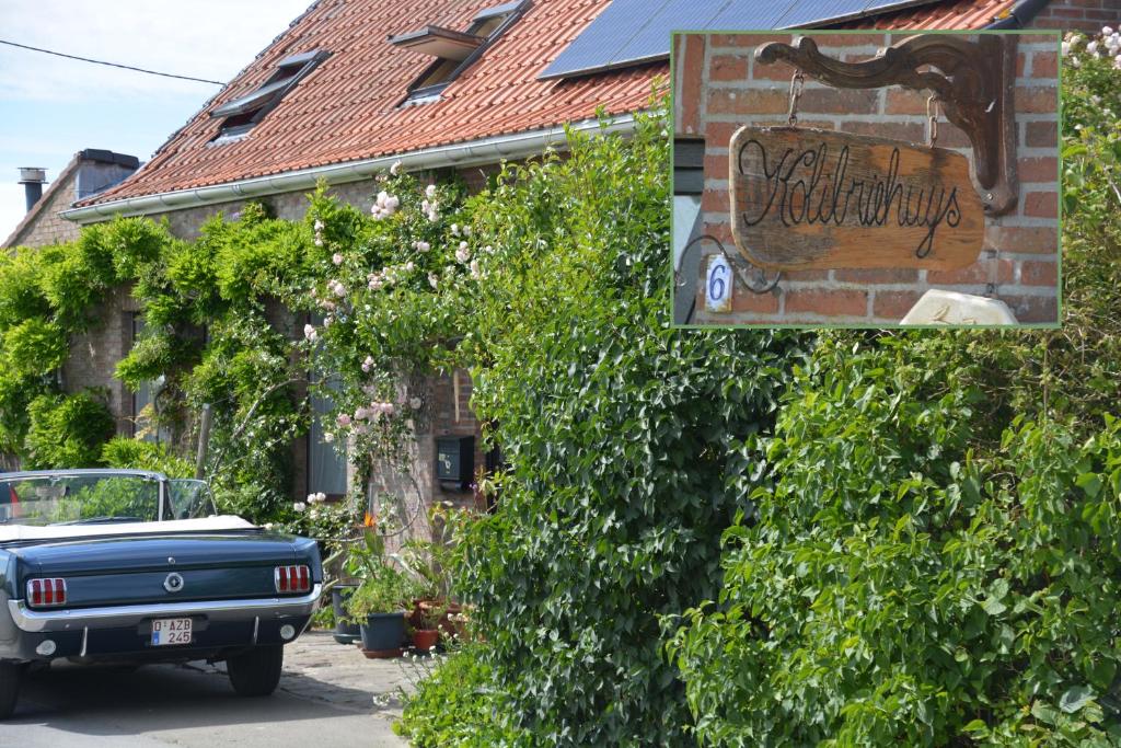 um carro estacionado em frente a um edifício com uma placa em Guesthouse Kolibriehuys em Nieuwkerke