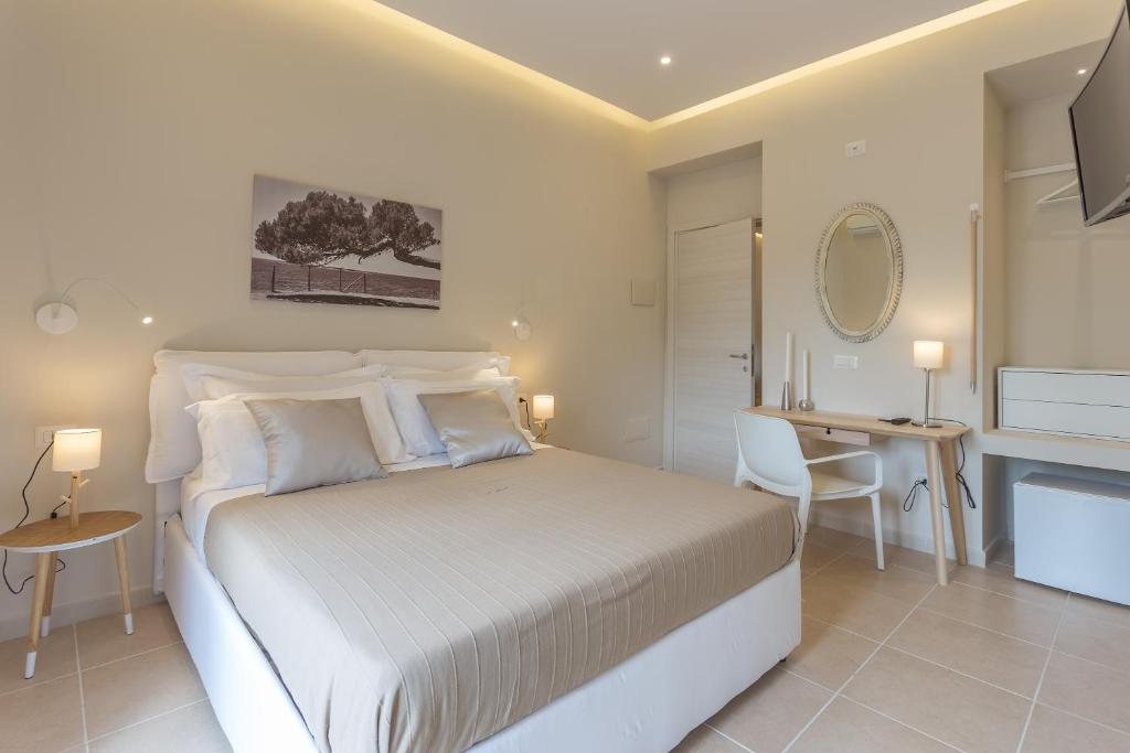 a white bedroom with a bed and a desk at Àstanza in Castellabate