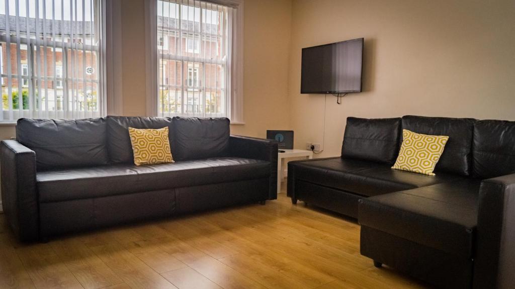 a living room with two black couches and a flat screen tv at The City Walls Gathering in Chester