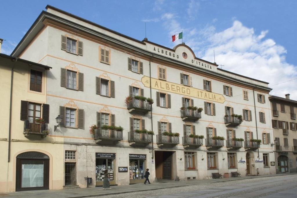 Un grand bâtiment blanc avec un drapeau en haut dans l'établissement Albergo Italia, à Varallo