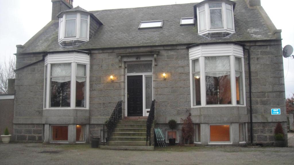 a gray house with white windows and a door at Station View Guest House in Dyce