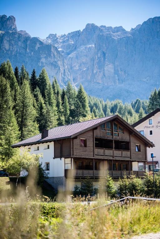 a wooden house with mountains in the background at Chalet Albric in Selva di Val Gardena