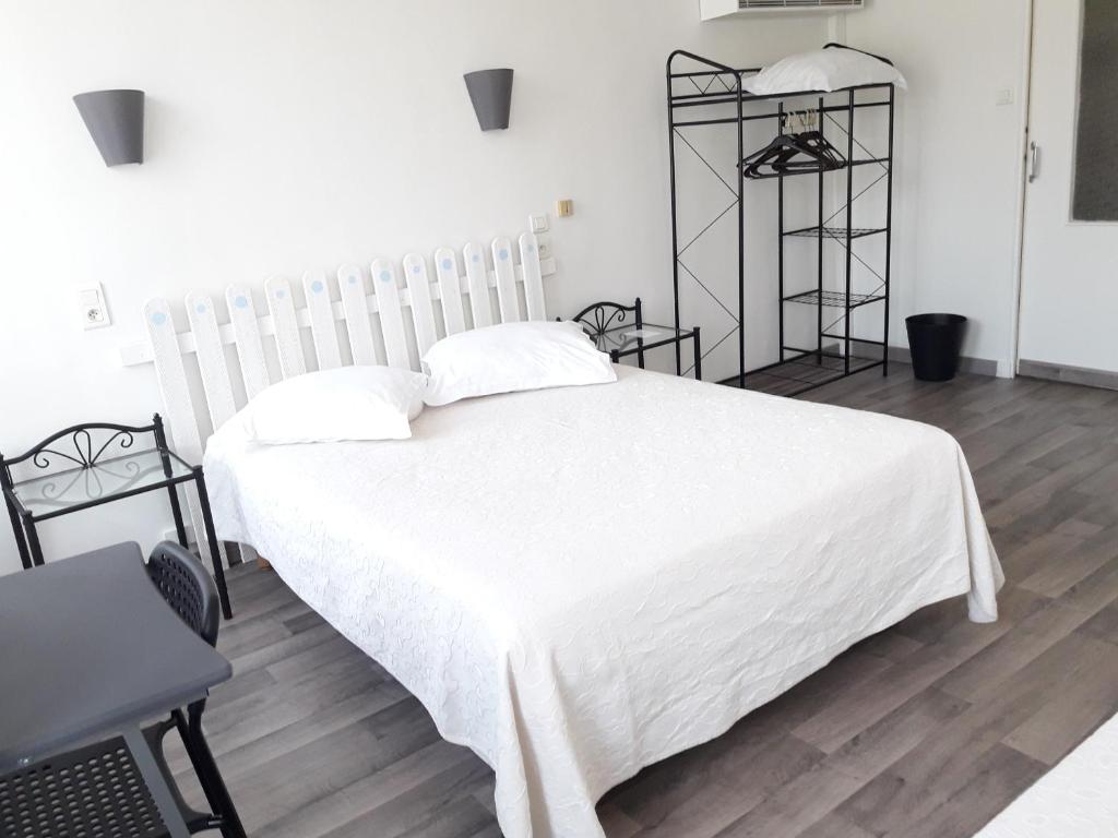 a bedroom with a white bed with a white blanket at Au Nouvel Hôtel in Toulon