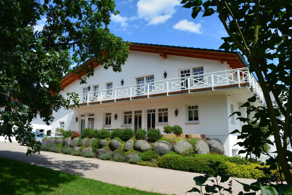 Biały dom z balkonem i krzakami w obiekcie Reiterhof und Pension Eichenhof w mieście Haiger