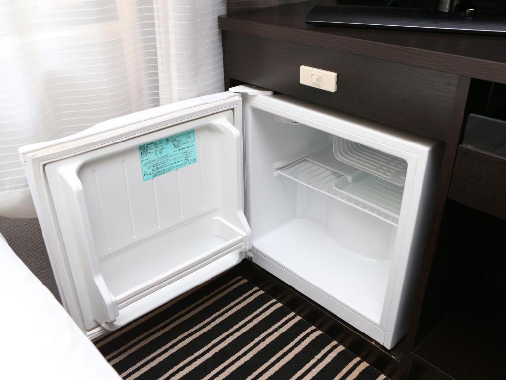 an empty refrigerator with its door open in a kitchen at APA Hotel Ningyocho Ekikita in Tokyo