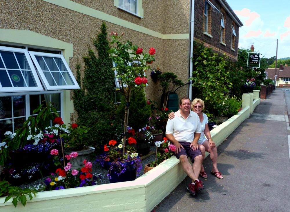 un hombre y una mujer sentados frente a un edificio con flores en The Guest House, en Abergavenny
