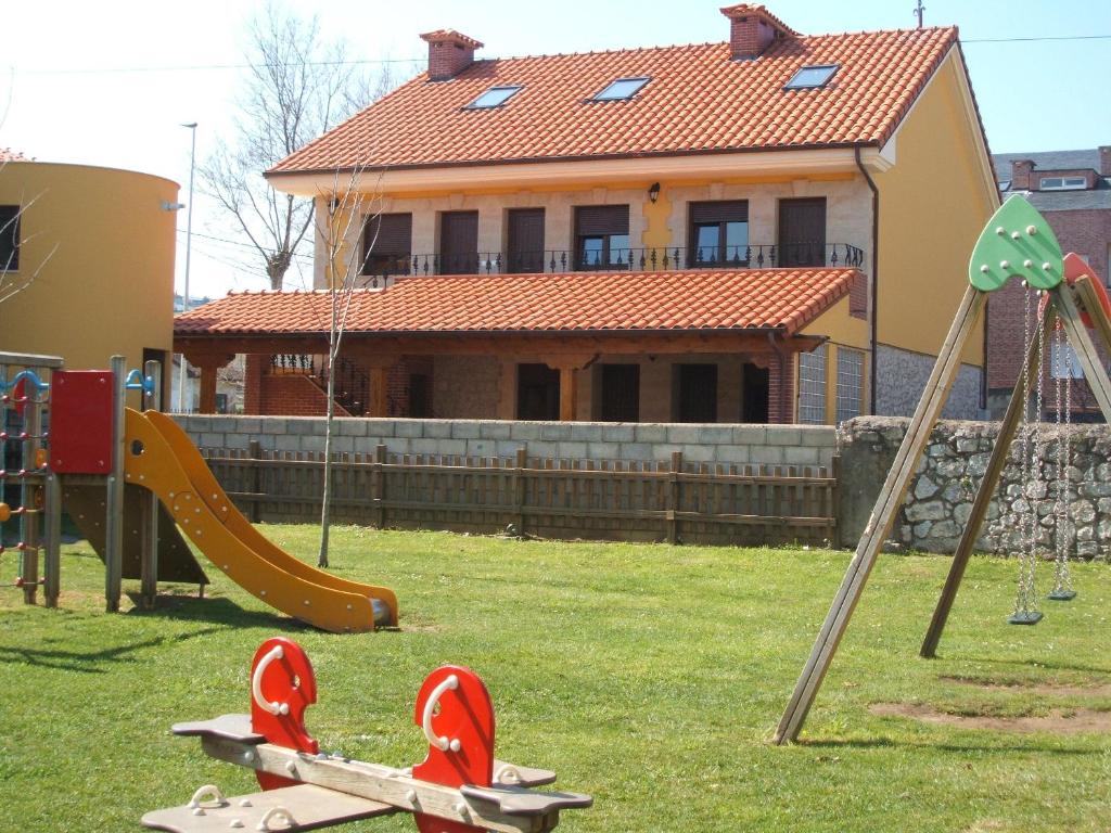 un parque infantil frente a una casa con una casa en Apartamentos Casa Bernabé, en Miengo