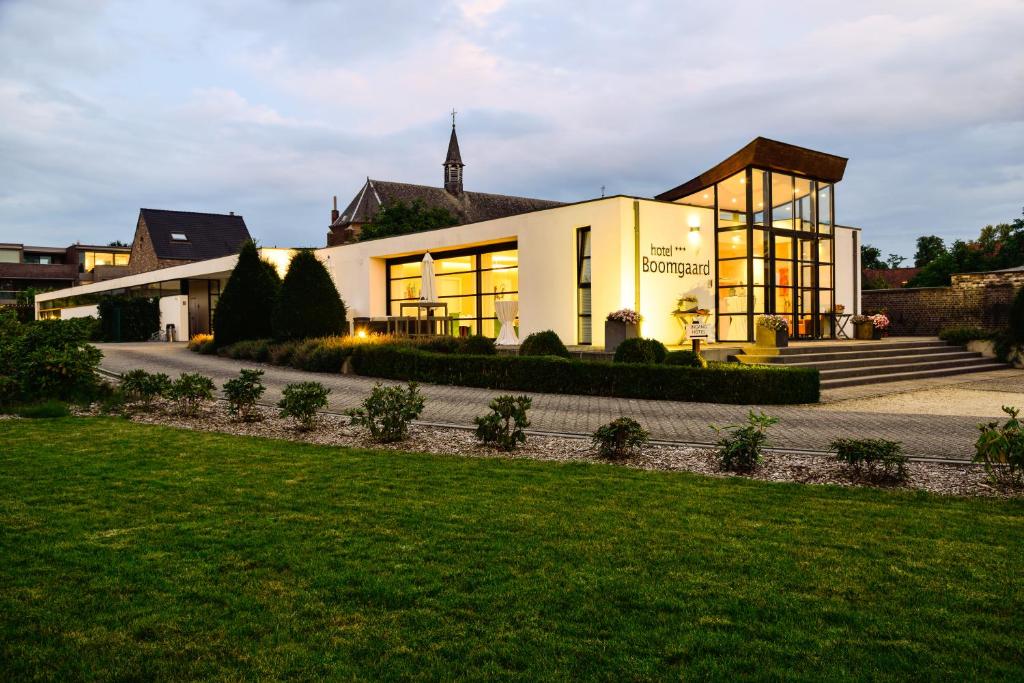 ein großes weißes Gebäude mit Fenstern und Rasen in der Unterkunft Hotel Boomgaard in Lanaken