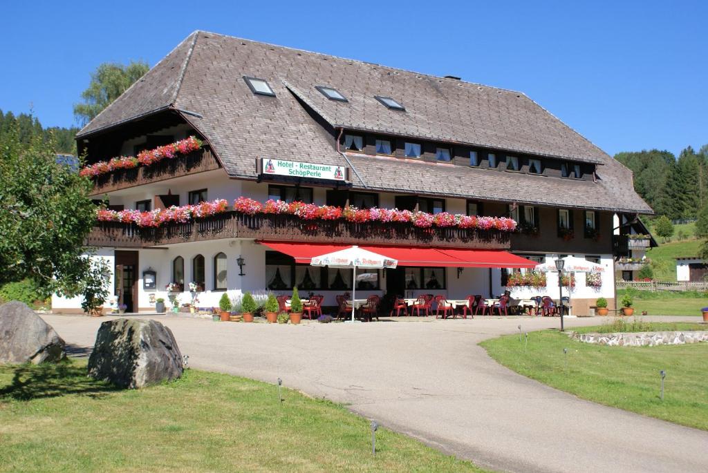 duży budynek ze stołami i parasolami przed nim w obiekcie SchöpPerle w mieście Häusern
