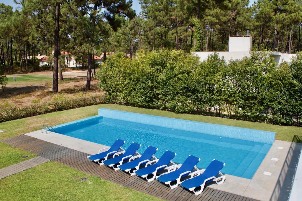 a pool with lounge chairs and a swimming pool at Design House Aroeira Golf in Charneca