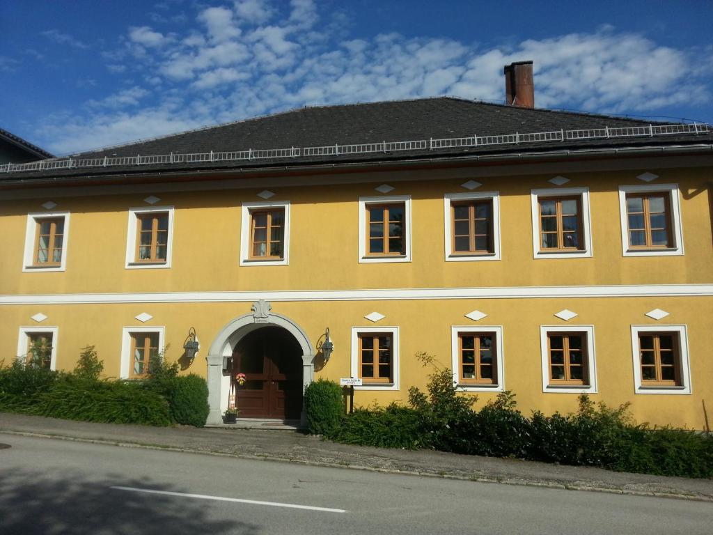 a large yellow building with an archway in a street at Privatzimmer Dimitrova in Ulrichsberg