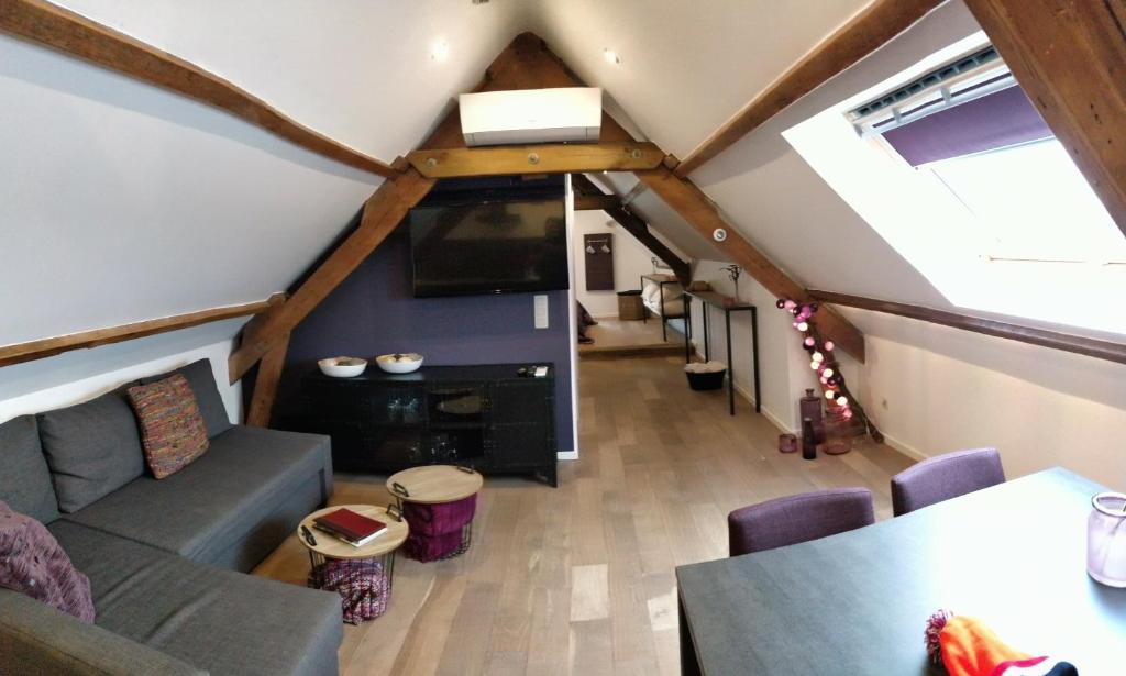 a living room with a couch and a tv in a attic at de Twie Keuninge in Maasmechelen