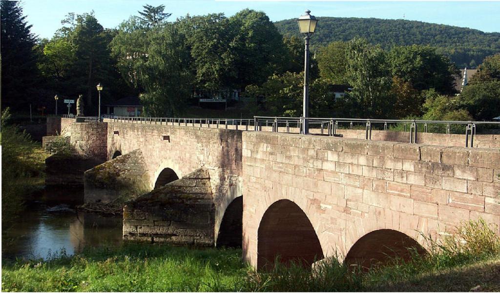 a stone bridge over a river with a street light at Pension zum Saale Blick in Bad Kissingen