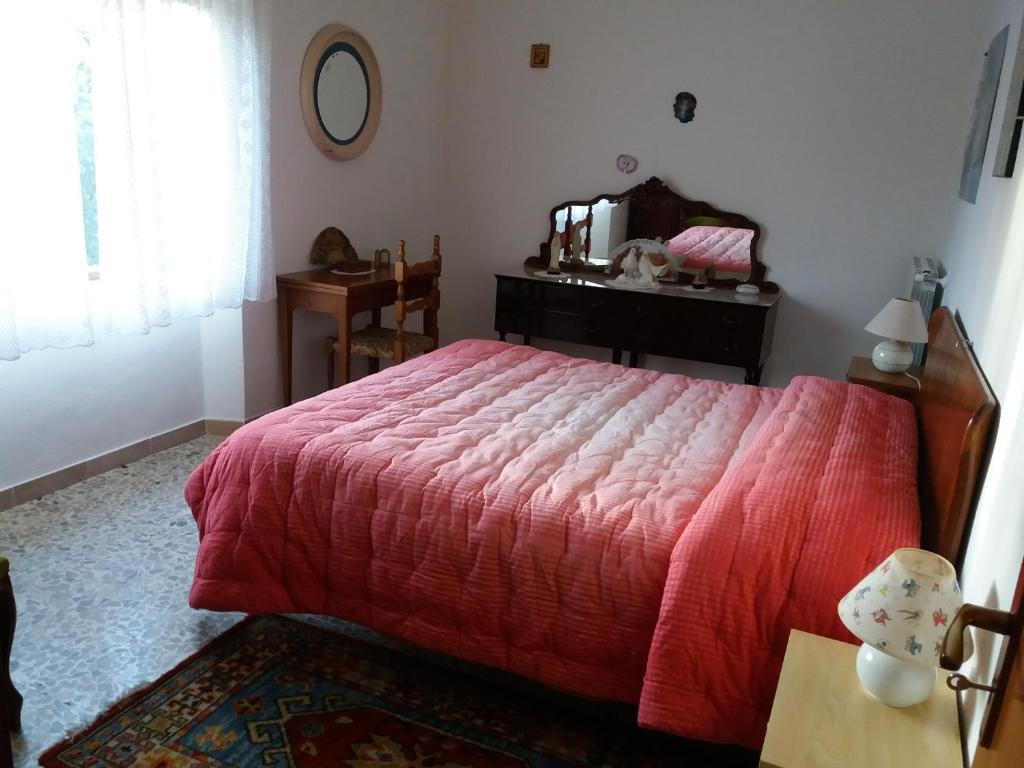 1 dormitorio con cama roja, tocador y espejo en Sa Nuche, en Mamoiada
