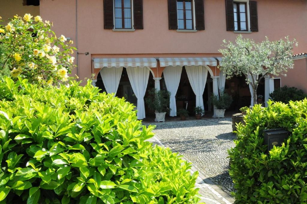 a garden in front of a pink building with bushes at La Corte B&B in Passirano