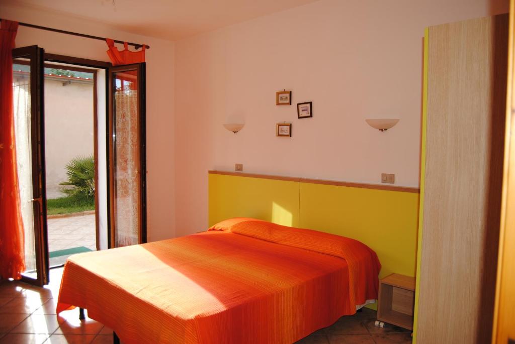 een slaapkamer met een bed met oranje en geel bij B&B ARENOSU25 in Alghero