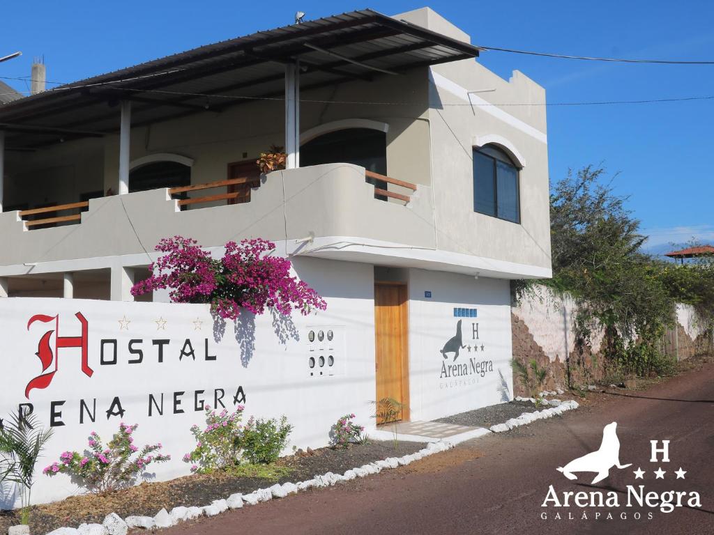 a white building with a sign in front of it at Hostal Arena Negra in Puerto Ayora