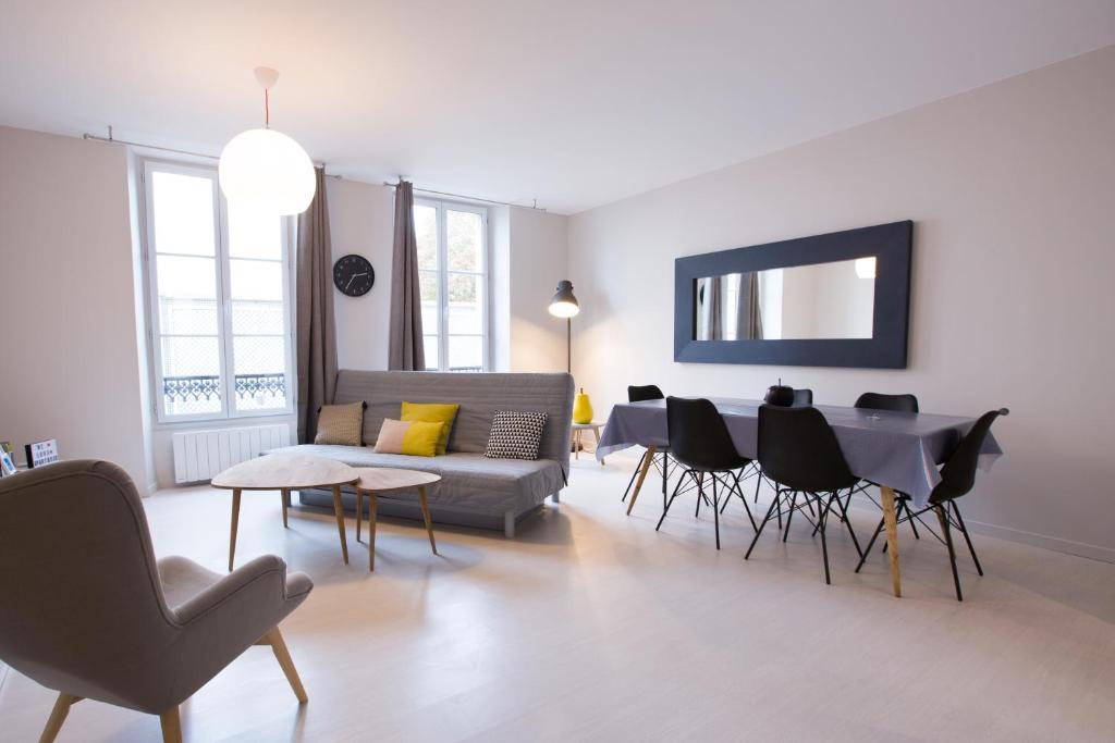 salon z kanapą, stołem i krzesłami w obiekcie Apart By Jo - Proc 2D w mieście Saint-Germain-en-Laye