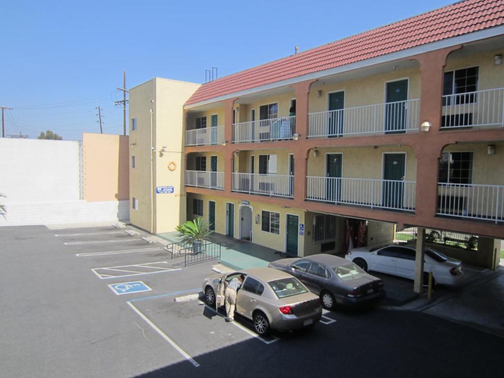 ein Apartmenthaus mit Autos auf einem Parkplatz in der Unterkunft Starlight Inn, Valley Blvd - Downtown LA in Los Angeles