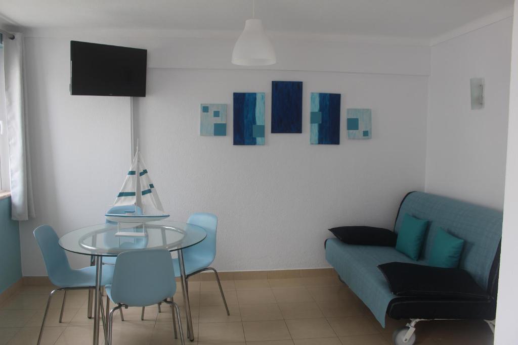 a living room with a blue couch and a glass table at Apartamento Mar in Quarteira