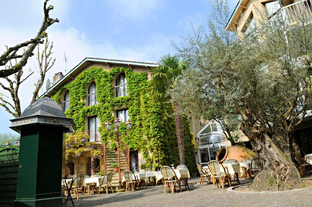 a building with tables and chairs in front of it at Noemys Gradignan - ex Cit'Hotel Le Chalet Lyrique in Gradignan