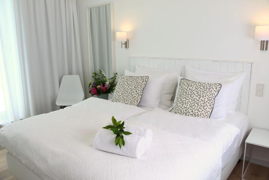 a white bedroom with a white bed with a plant on it at Berdorfer Eck - Bed&Breakfast in Berdorf