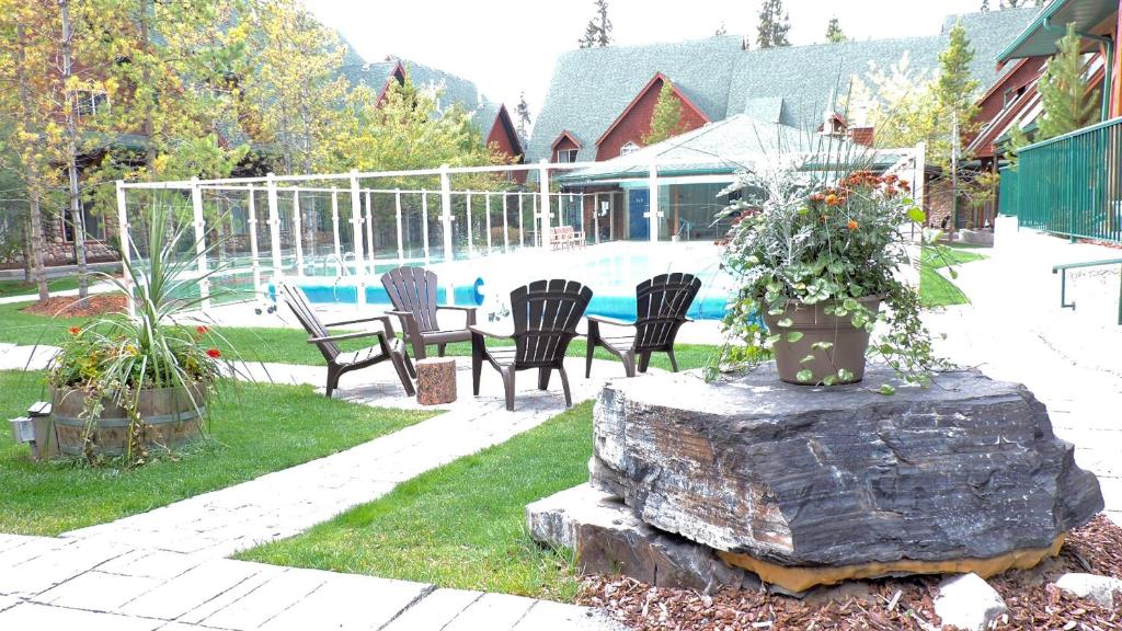 einen Garten mit Stühlen, einem Tisch und einem Pool in der Unterkunft Fenwick Vacation Rentals OPEN Pool & Hot tub in Canmore