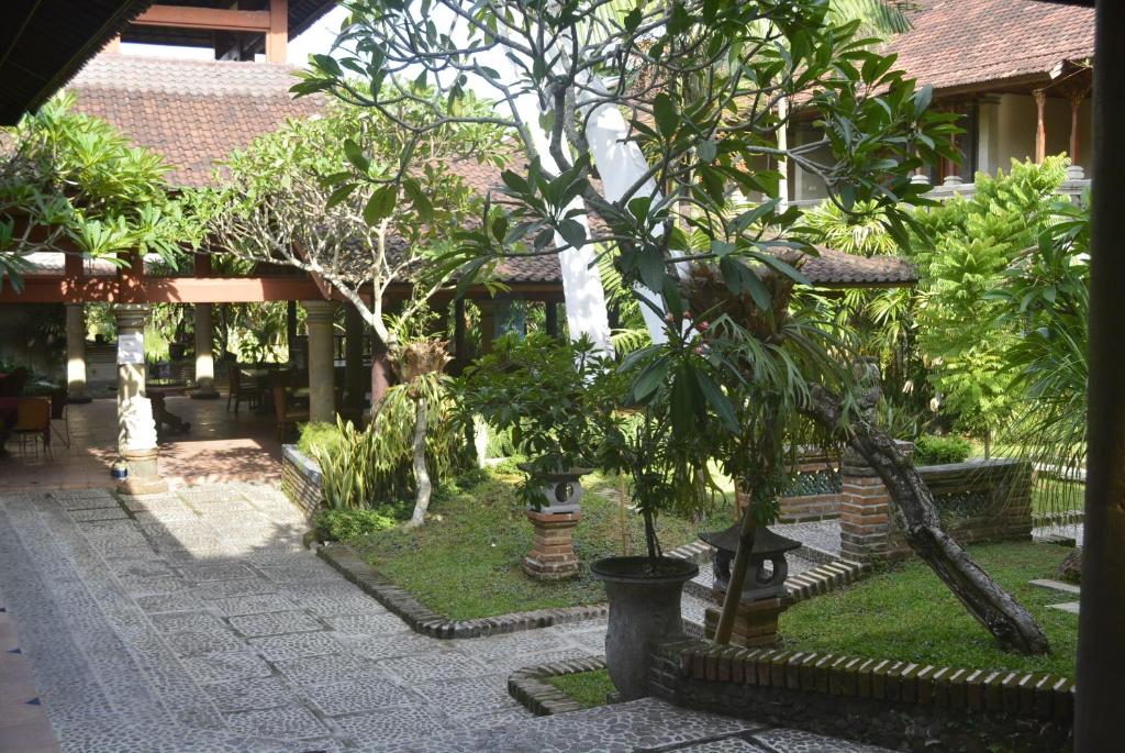 a garden with trees and a building with a courtyard at Puri Padi in Ubud