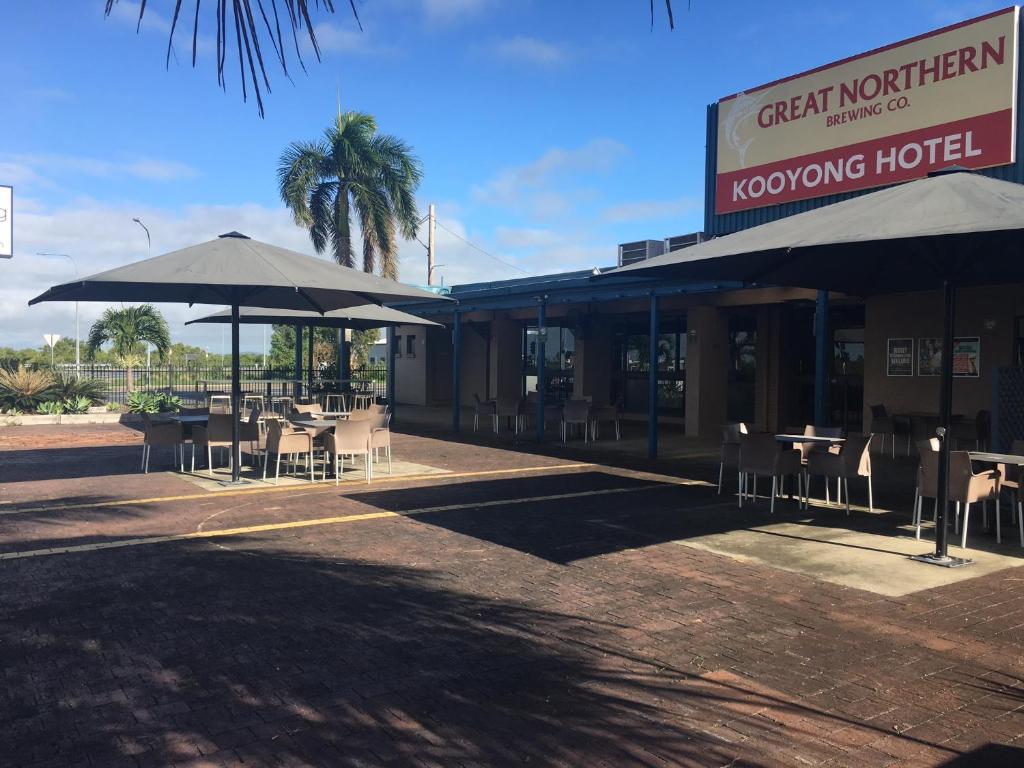 ein Restaurant mit Tischen und Sonnenschirmen davor in der Unterkunft Kooyong Hotel in Mackay