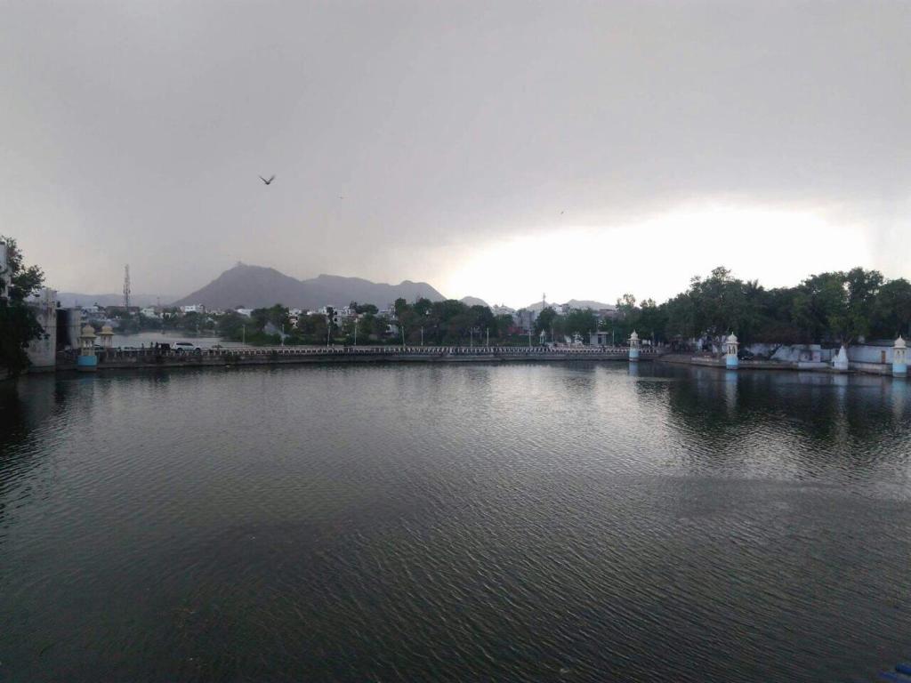 a large body of water with trees and buildings at Devi Villa in Udaipur