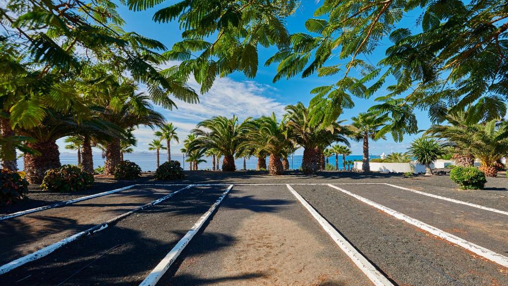 an empty road with palm trees and the ocean at Hipotels Natura Palace Adults Only in Playa Blanca