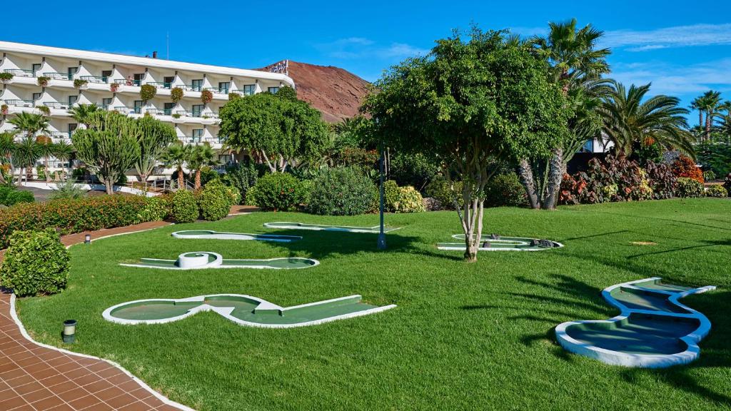 a resort with slides in the grass in front of a building at Hipotels Natura Palace Adults Only in Playa Blanca
