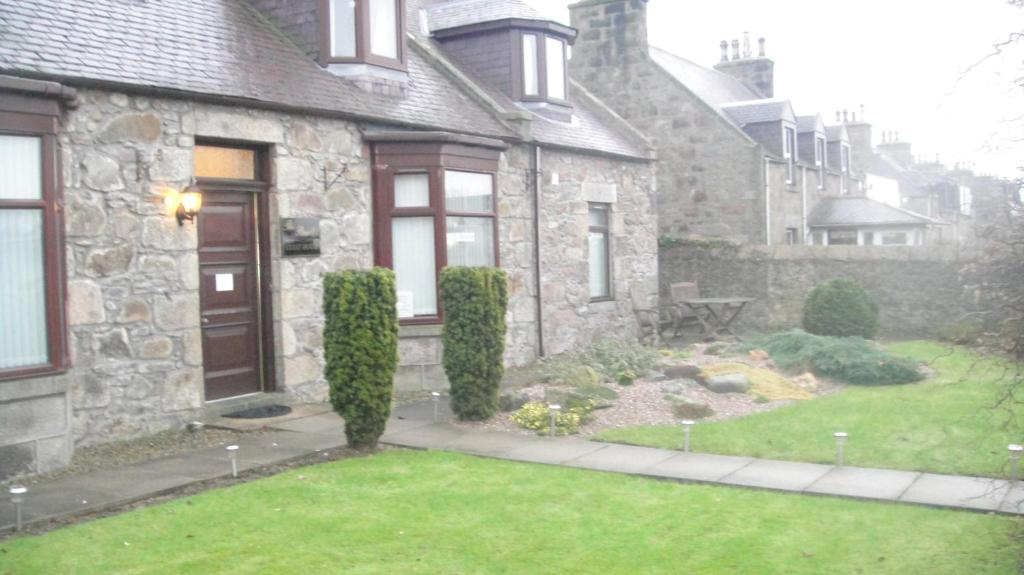 una casa in pietra con un giardino di fronte di Beeches Guest House a Dyce