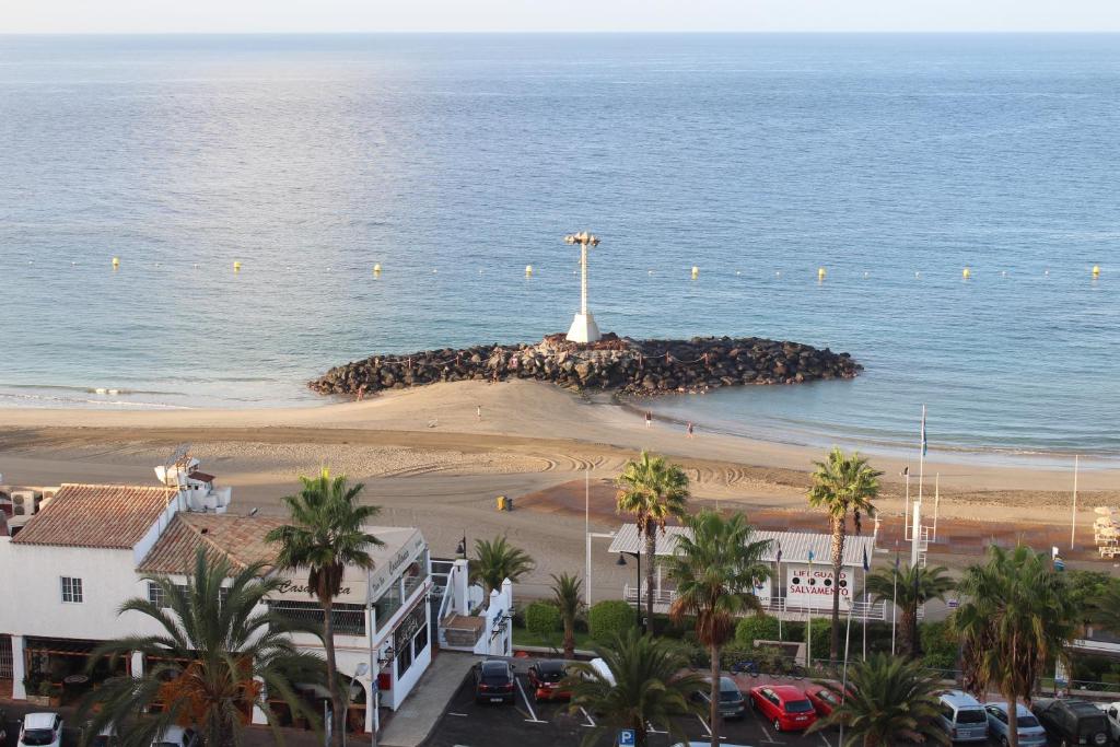 a group of people standing around a lighthouse on the beach at Apartamentos Vista Bahia in Los Cristianos