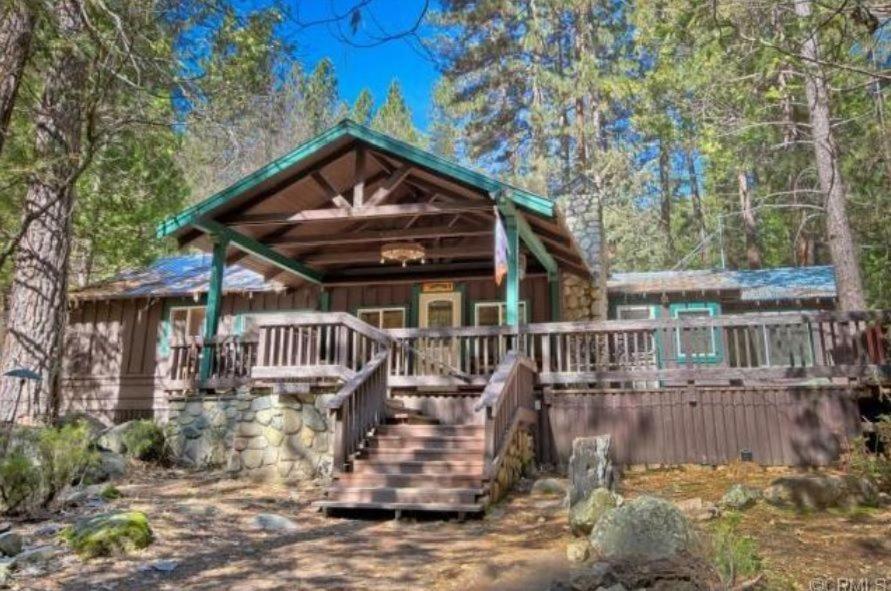 a log home with a large deck in the woods at 95R The Little Creek Cabin in Wawona